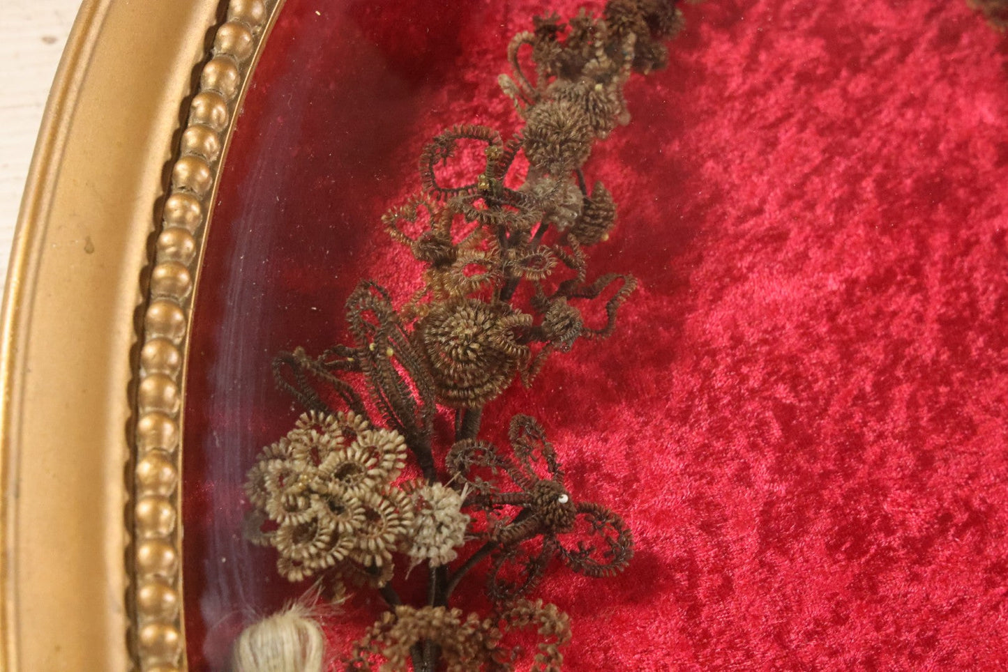 Lot 008 - Antique Victorian Human Hair Work Wreath In Oval Shadow Box With Bubble Glass, Refurbished Faux Red Velvet Back And Surround, 16" x 22"