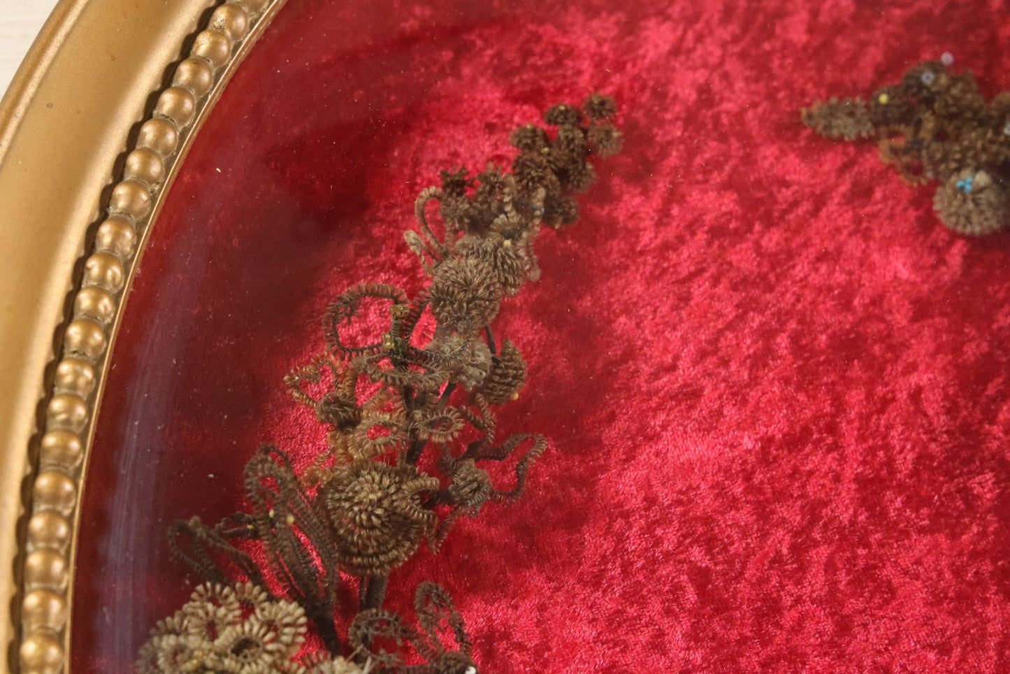 Lot 008 - Antique Victorian Human Hair Work Wreath In Oval Shadow Box With Bubble Glass, Refurbished Faux Red Velvet Back And Surround, 16" x 22"