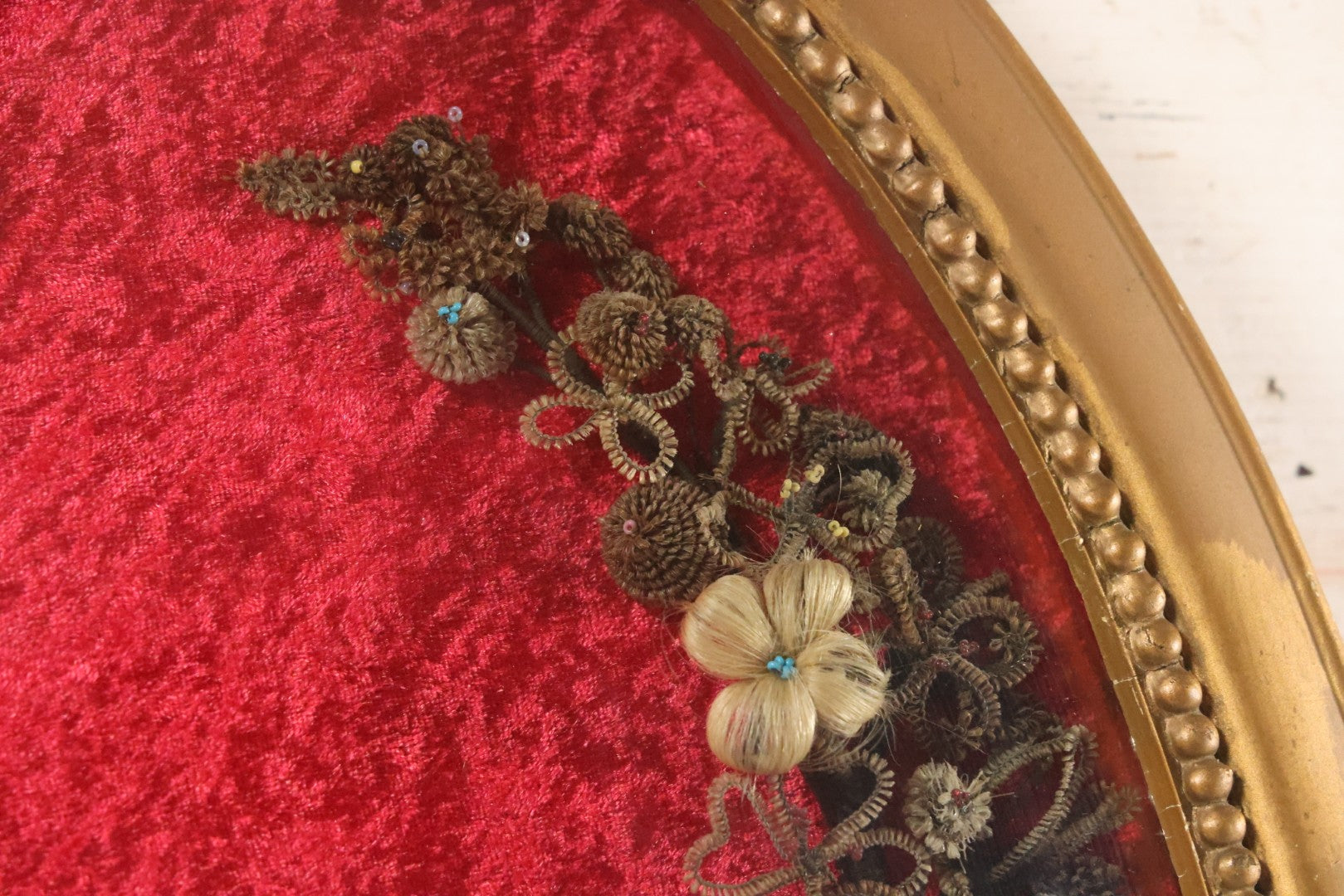 Lot 008 - Antique Victorian Human Hair Work Wreath In Oval Shadow Box With Bubble Glass, Refurbished Faux Red Velvet Back And Surround, 16" x 22"