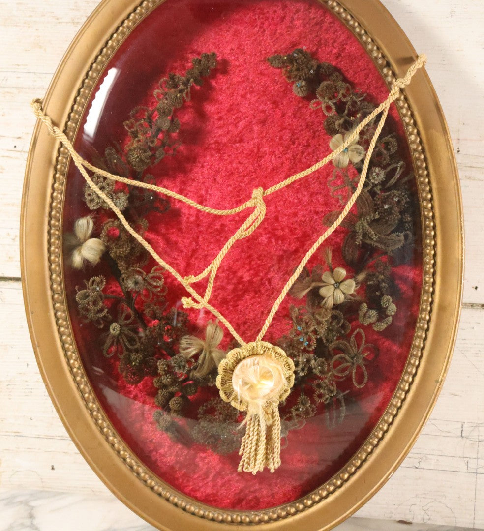 Lot 008 - Antique Victorian Human Hair Work Wreath In Oval Shadow Box With Bubble Glass, Refurbished Faux Red Velvet Back And Surround, 16" x 22"