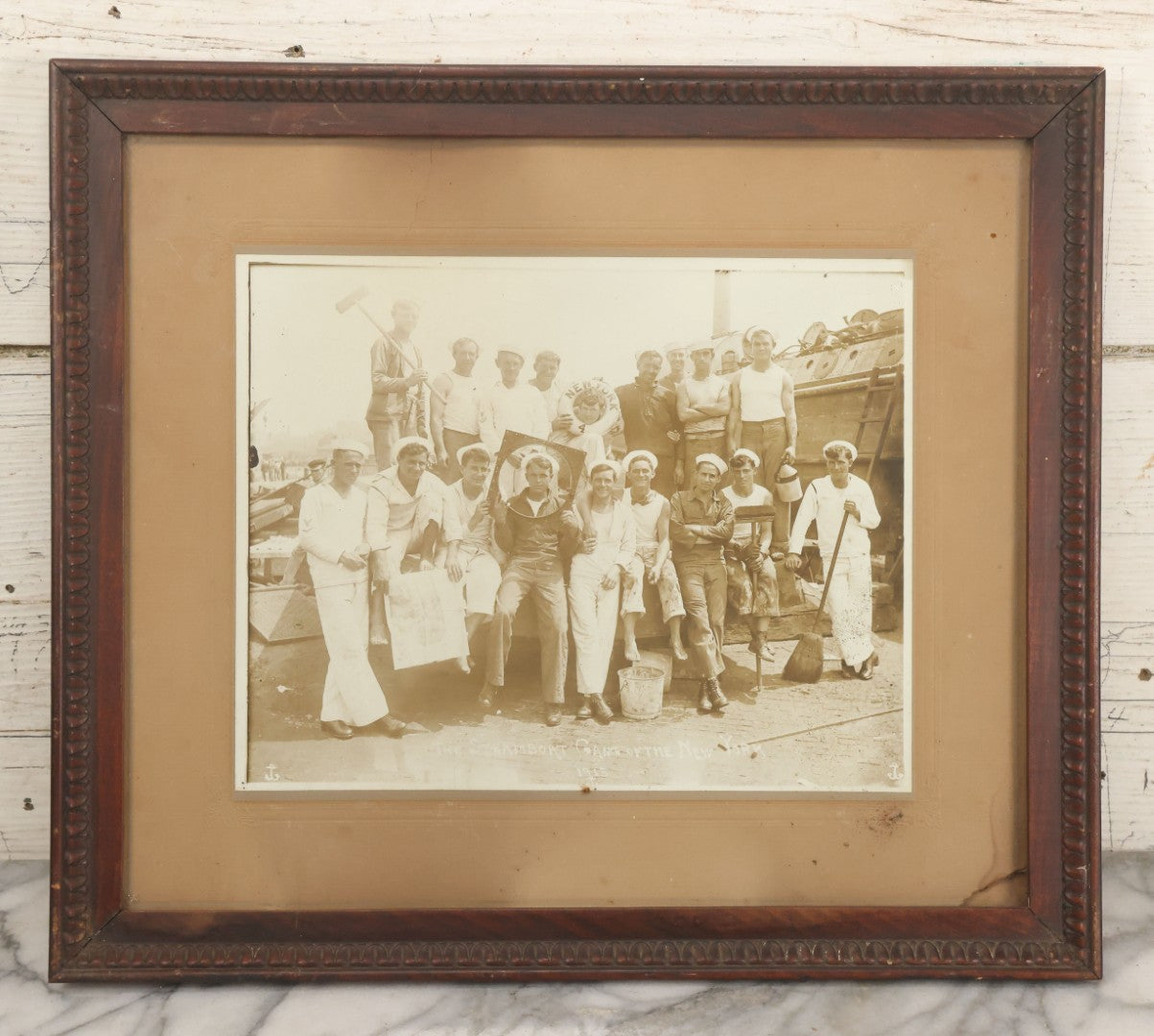 Lot 019 - Antique Boarded Photograph In Frame Of "The Steamboat Gang Of The New York," 1915, Occupational Photos Of Navy Sailors On Dock, With Tools Of The Trade, Other Workers In Background, U.S.S. New York (BB-34), 15-1/2" x 13-1/2"