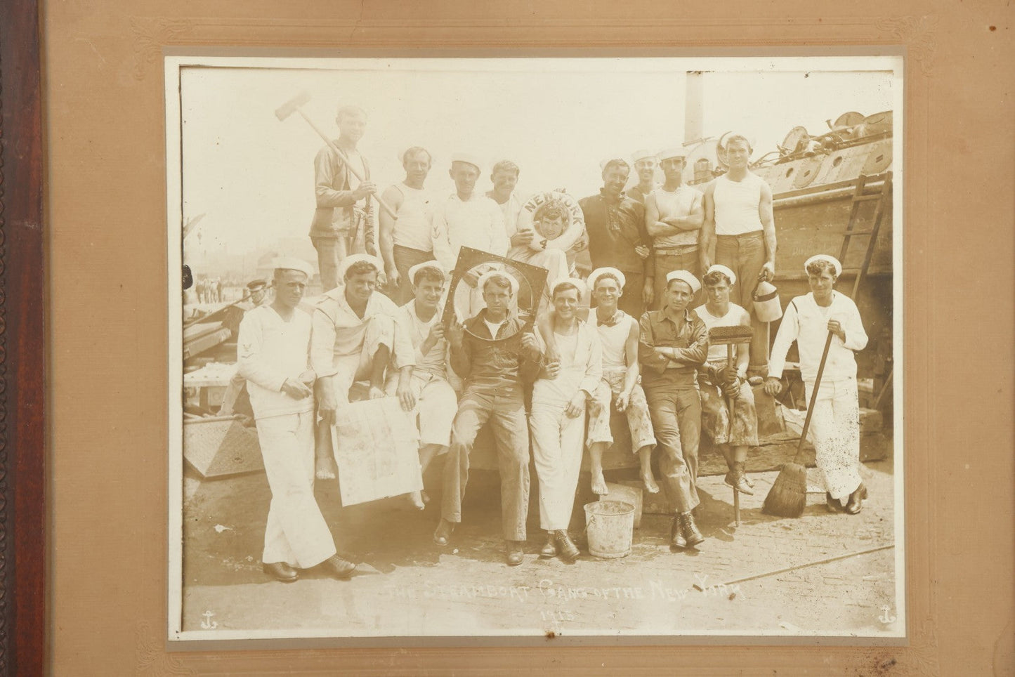 Lot 019 - Antique Boarded Photograph In Frame Of "The Steamboat Gang Of The New York," 1915, Occupational Photos Of Navy Sailors On Dock, With Tools Of The Trade, Other Workers In Background, U.S.S. New York (BB-34), 15-1/2" x 13-1/2"