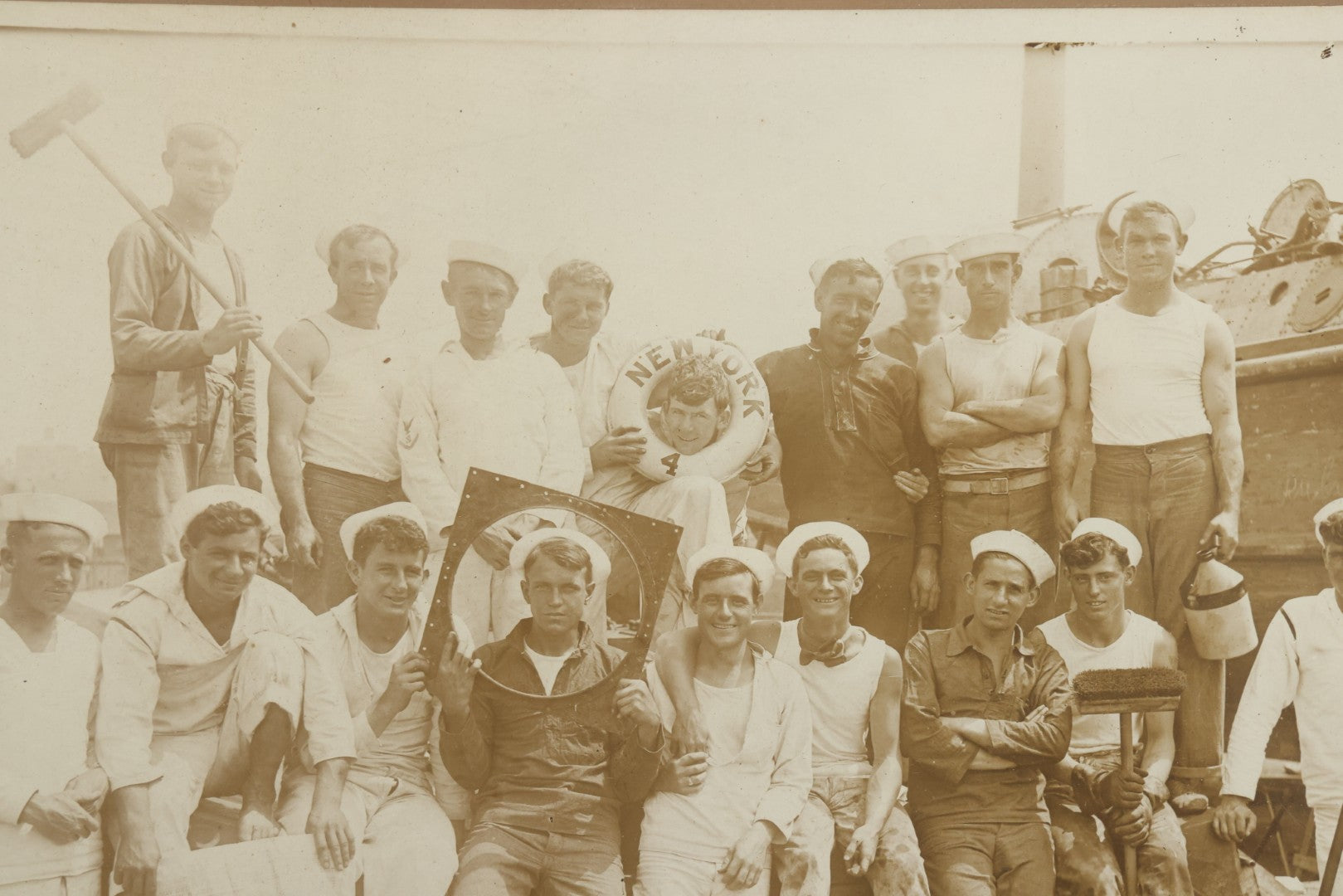 Lot 019 - Antique Boarded Photograph In Frame Of "The Steamboat Gang Of The New York," 1915, Occupational Photos Of Navy Sailors On Dock, With Tools Of The Trade, Other Workers In Background, U.S.S. New York (BB-34), 15-1/2" x 13-1/2"