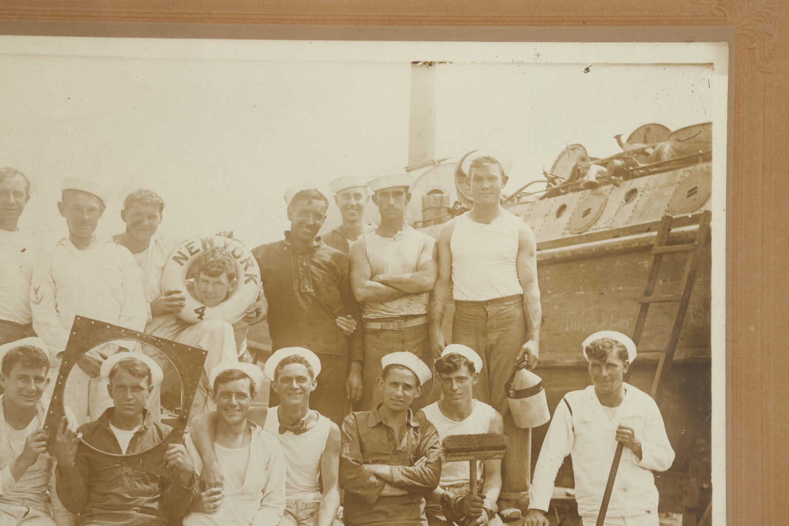 Lot 019 - Antique Boarded Photograph In Frame Of "The Steamboat Gang Of The New York," 1915, Occupational Photos Of Navy Sailors On Dock, With Tools Of The Trade, Other Workers In Background, U.S.S. New York (BB-34), 15-1/2" x 13-1/2"