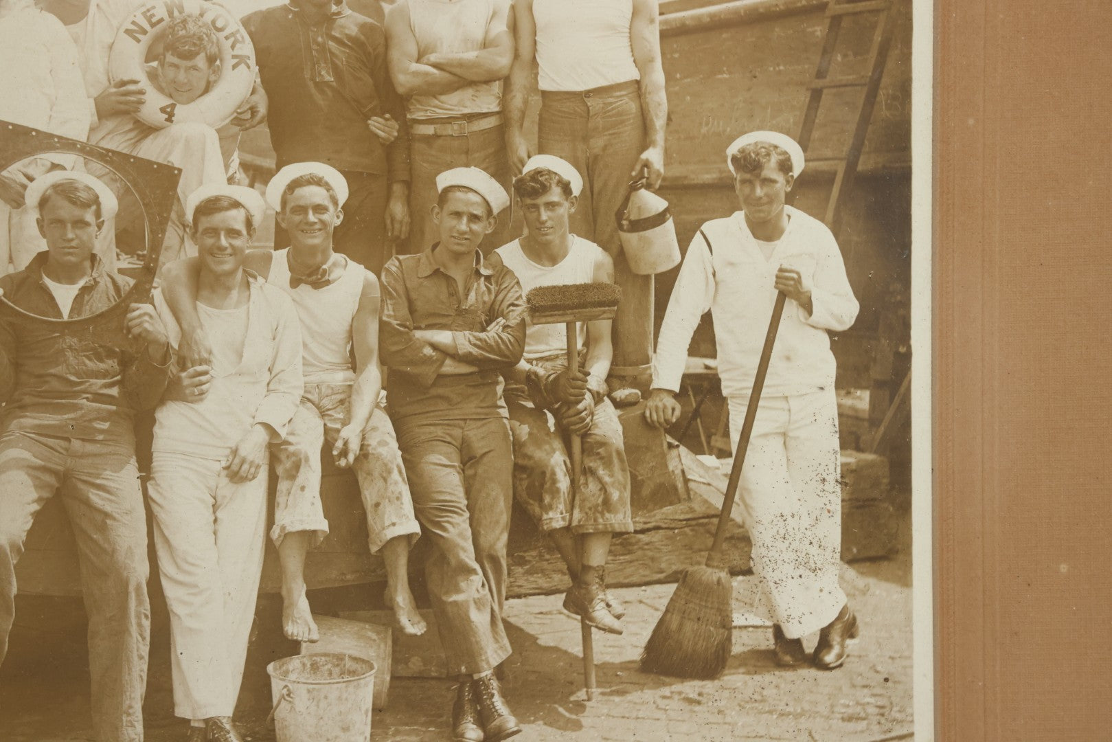 Lot 019 - Antique Boarded Photograph In Frame Of "The Steamboat Gang Of The New York," 1915, Occupational Photos Of Navy Sailors On Dock, With Tools Of The Trade, Other Workers In Background, U.S.S. New York (BB-34), 15-1/2" x 13-1/2"