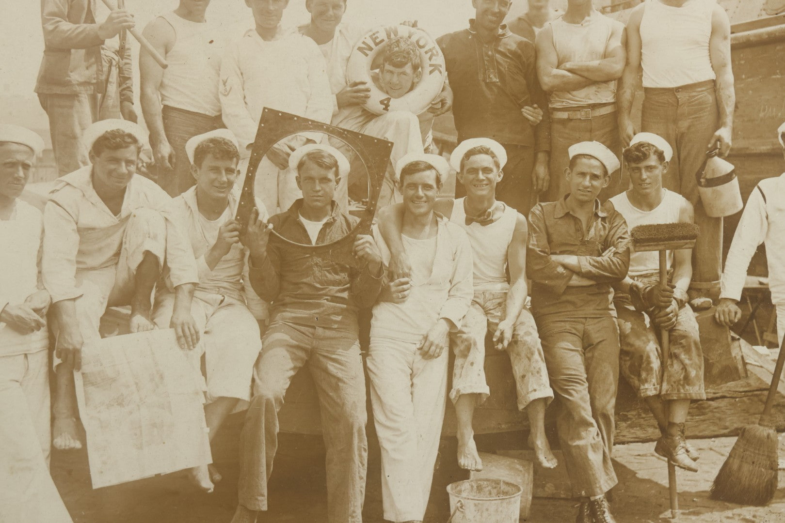 Lot 019 - Antique Boarded Photograph In Frame Of "The Steamboat Gang Of The New York," 1915, Occupational Photos Of Navy Sailors On Dock, With Tools Of The Trade, Other Workers In Background, U.S.S. New York (BB-34), 15-1/2" x 13-1/2"