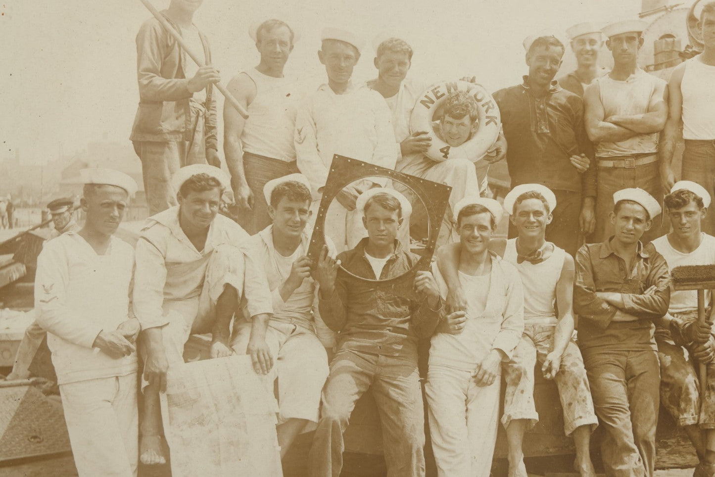 Lot 019 - Antique Boarded Photograph In Frame Of "The Steamboat Gang Of The New York," 1915, Occupational Photos Of Navy Sailors On Dock, With Tools Of The Trade, Other Workers In Background, U.S.S. New York (BB-34), 15-1/2" x 13-1/2"