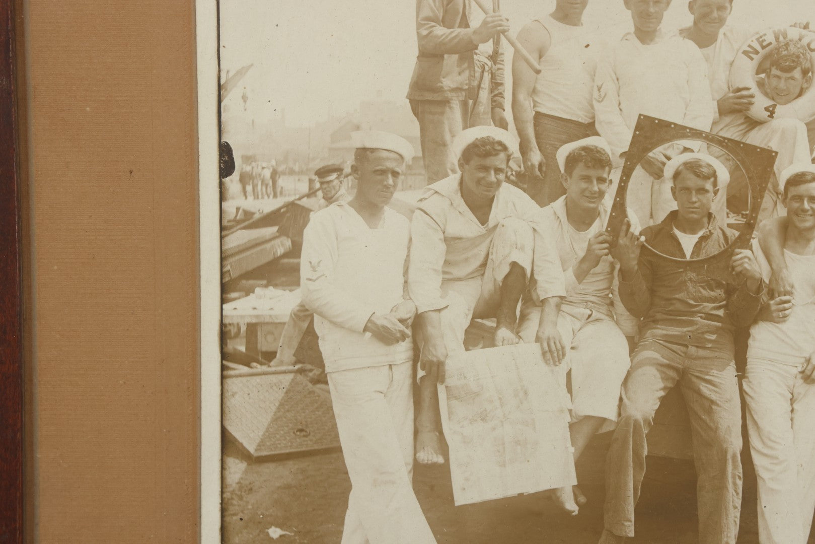 Lot 019 - Antique Boarded Photograph In Frame Of "The Steamboat Gang Of The New York," 1915, Occupational Photos Of Navy Sailors On Dock, With Tools Of The Trade, Other Workers In Background, U.S.S. New York (BB-34), 15-1/2" x 13-1/2"