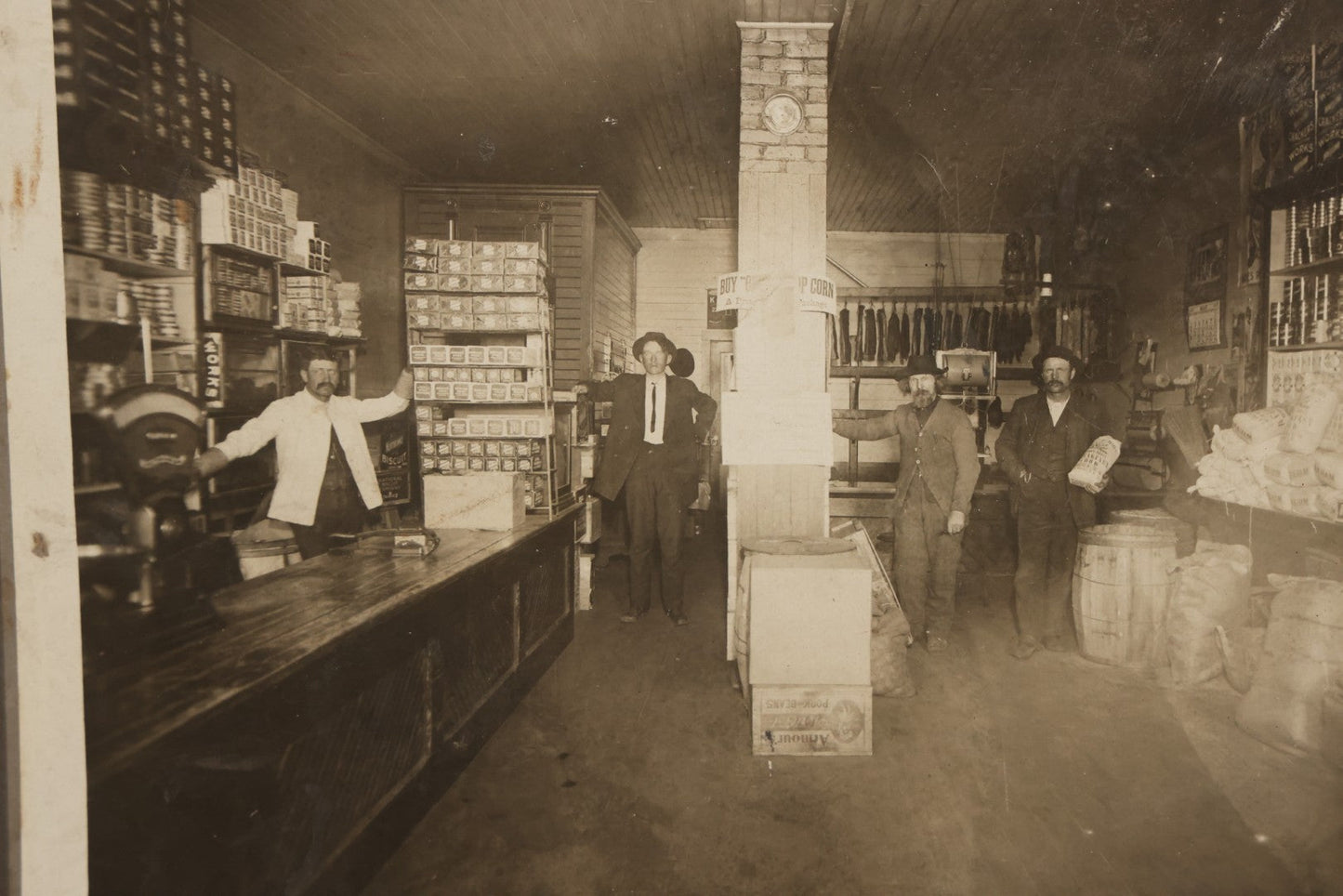 Lot 080 - Antique Boarded Occupational Photograph Of The Interior Of A General Store With Four Men In Frame, Many Products, Advertisements, Note Corner Losses