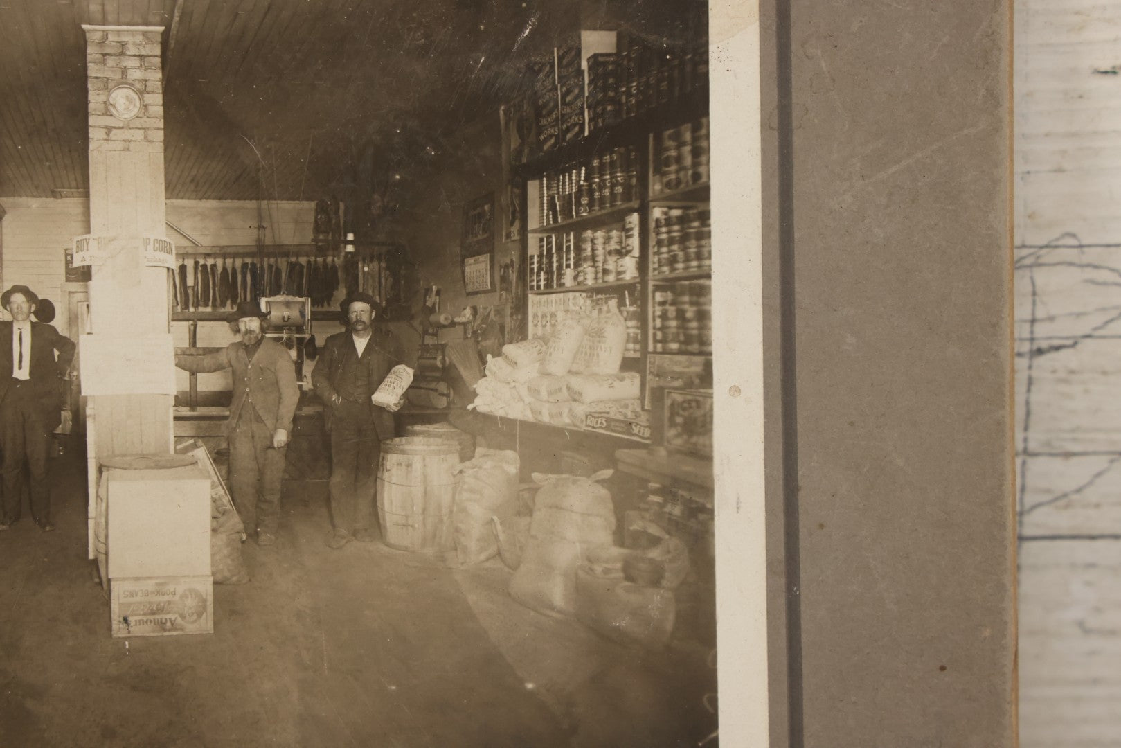 Lot 080 - Antique Boarded Occupational Photograph Of The Interior Of A General Store With Four Men In Frame, Many Products, Advertisements, Note Corner Losses