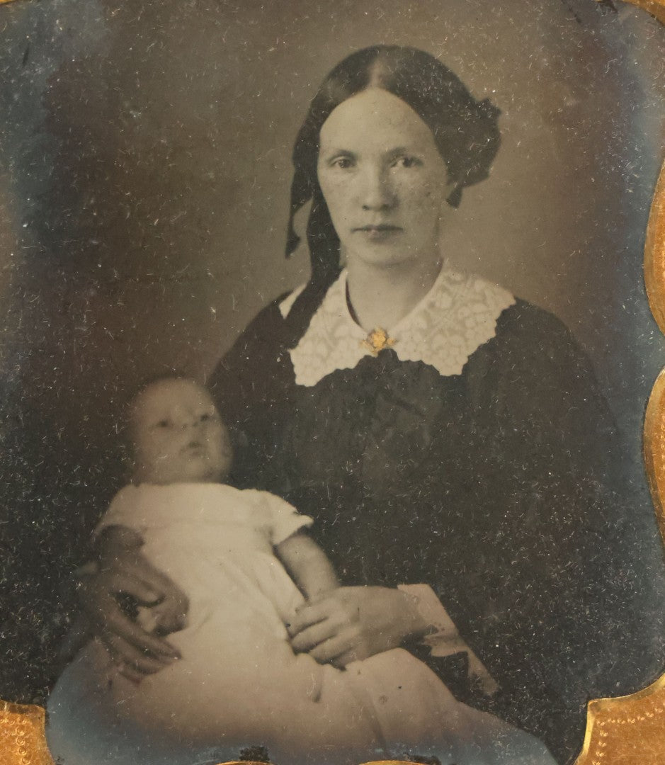 Lot 027 - Antique 1/6th Plate Ambrotype Photograph Of Young Mother Holding Newborn Baby, Wearing Tinted Jewelry, In Full Leatherette Union Case, Note Spine Repaired With Tape