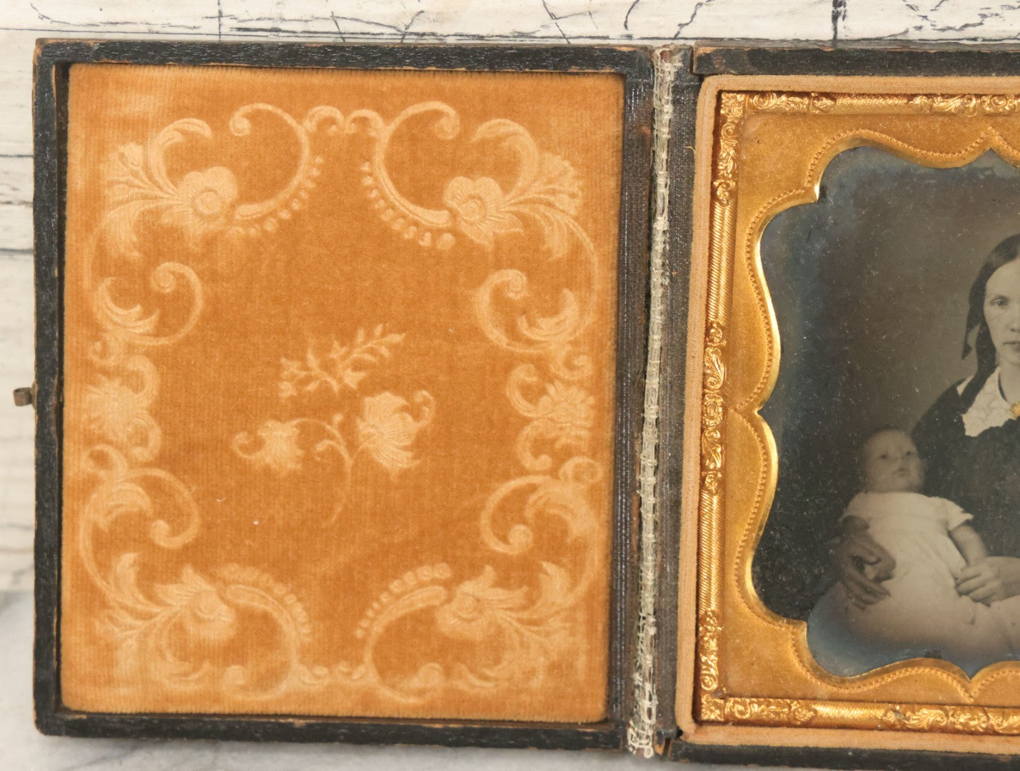 Lot 027 - Antique 1/6th Plate Ambrotype Photograph Of Young Mother Holding Newborn Baby, Wearing Tinted Jewelry, In Full Leatherette Union Case, Note Spine Repaired With Tape