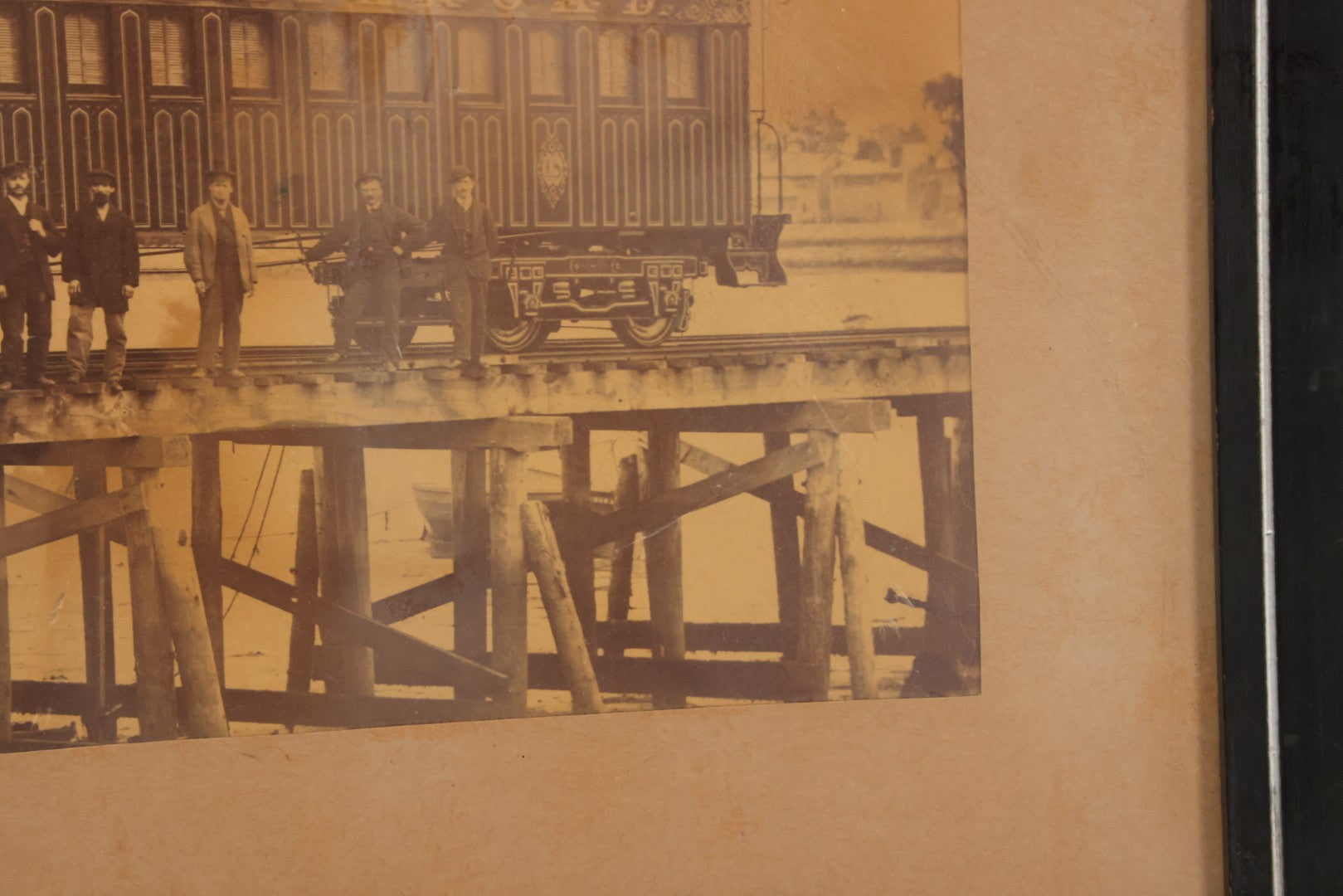 Lot 037 - Antique Boarded Occupational Photograph Of Newly Built Eastern Railroad Passenger Train Car, With Workers Pictured On Train Track, In Front Of Harbor, In Frame, Note Water Stains, 15-5/8" x 11-1/4"
