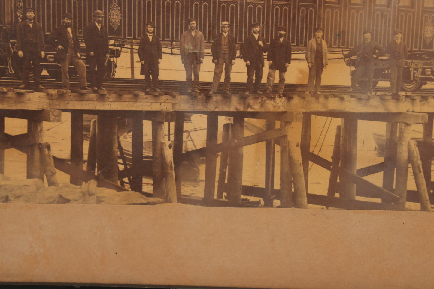 Lot 037 - Antique Boarded Occupational Photograph Of Newly Built Eastern Railroad Passenger Train Car, With Workers Pictured On Train Track, In Front Of Harbor, In Frame, Note Water Stains, 15-5/8" x 11-1/4"