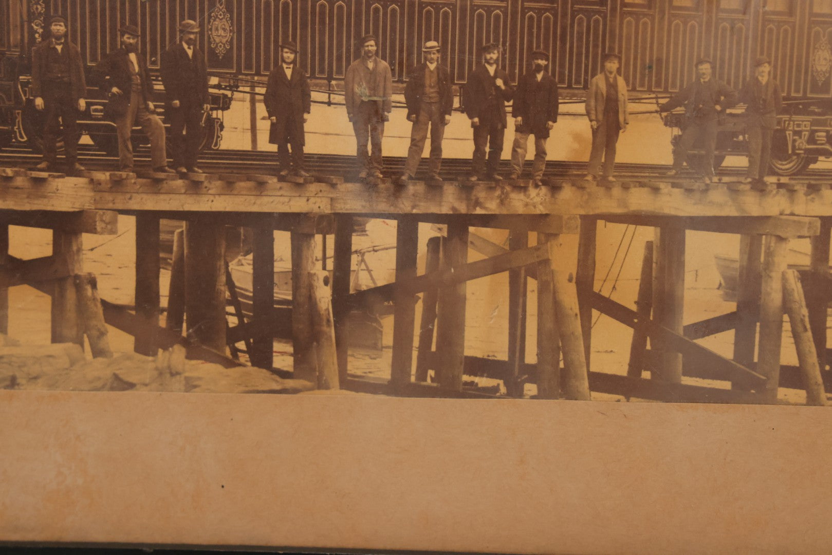Lot 037 - Antique Boarded Occupational Photograph Of Newly Built Eastern Railroad Passenger Train Car, With Workers Pictured On Train Track, In Front Of Harbor, In Frame, Note Water Stains, 15-5/8" x 11-1/4"