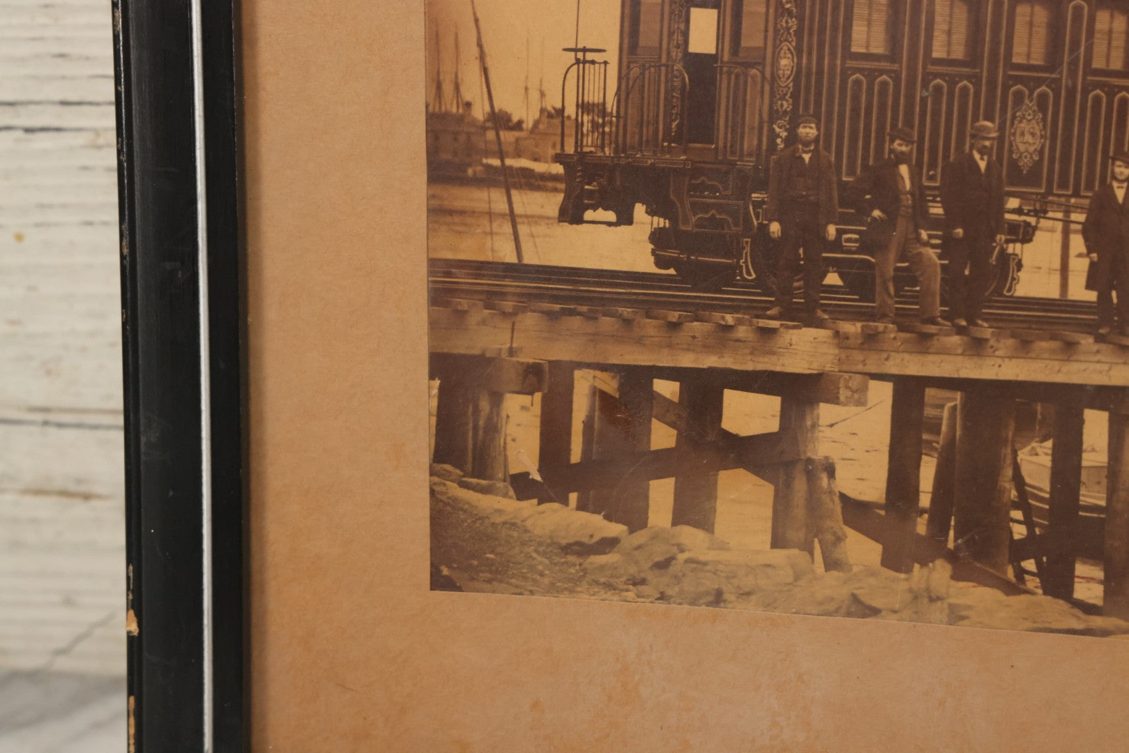 Lot 037 - Antique Boarded Occupational Photograph Of Newly Built Eastern Railroad Passenger Train Car, With Workers Pictured On Train Track, In Front Of Harbor, In Frame, Note Water Stains, 15-5/8" x 11-1/4"