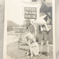 Lot 126 - Vintage 5 x 7 Snapshot Photograph Of Two Young Women Outside An Antique Store Pretending To Drink Whiskey From Old Jugs