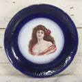 Lot 082 - Antique Decorative Transferware Plate With Blue Rim Featuring Pretty Woman With Long Brown Hair And Rose After G. Bonfits, By Royal La Belle, Wheeling Potteries Co., With Wire Hanger, 13" Diameter