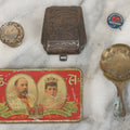 Lot 093 - Antique 5 Item Metals Grouping Including "Mother" Perfume Bottle Top, King Edward VII & Queen Alexandra Commemorative Tin, Nude Woman Art Deco Fragment, First Birthday Pin, And Teaspoon