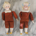 Lot 097 - Pair Of Antique Bisque Dolls With Boy And Girl With Blue Bows And Sawdust Filled Cloth Bodies, Note Girl's Head Detached, Holes In Bodies, With Sawdust Leakage, 6-1/4" Height Each