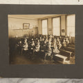 Lot 060 - Antique Boarded Photograph Of The Interior Of A 2Nd Grade Classroom With School Children, Teacher Holding Books,