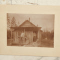 Lot 096 - Antique Boarded Photograph Of Two Men And Two Women Posing On The Stoop Of A Hunting Cabin, Men Holding Rifles