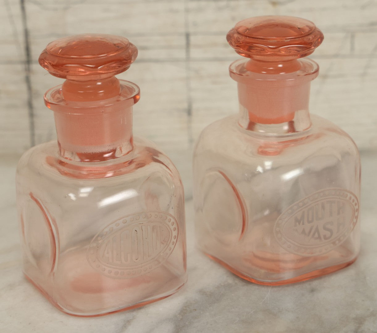 Lot 065 - Pair Of Antique Pink Depression Glass Etched Vanity Bathroom Jars With Stoppers, Alcohol And Mouthwash, 4-3/8" Height Each