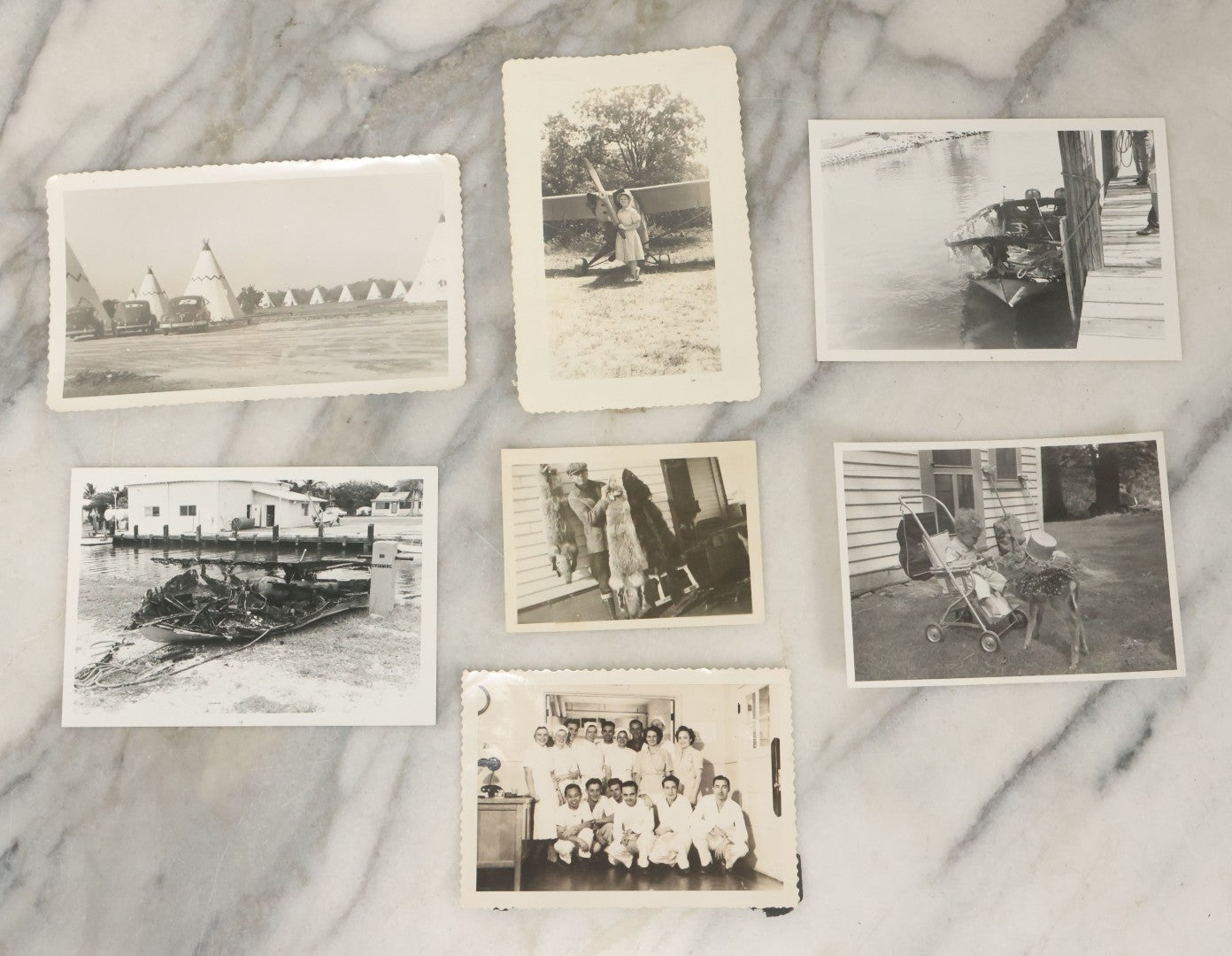 Lot 098 - Grouping Of Seven Vintage Snap Shot Photographs Including Child With Baby Deer Fawn, Man With Pelts, Teepee Campsite, Burned Boat, Etc.