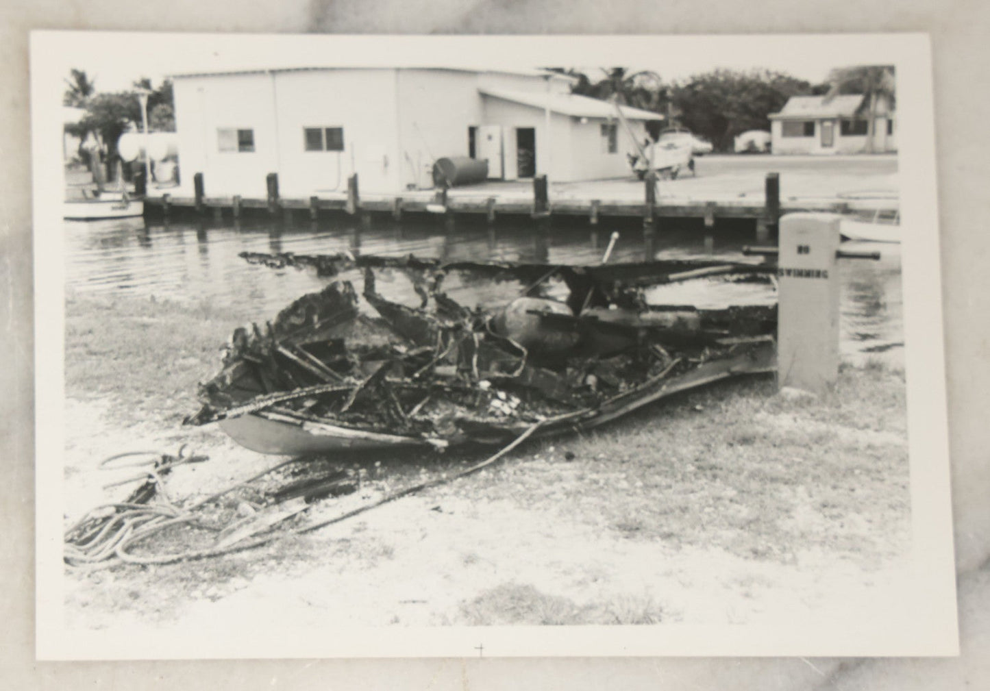 Lot 098 - Grouping Of Seven Vintage Snap Shot Photographs Including Child With Baby Deer Fawn, Man With Pelts, Teepee Campsite, Burned Boat, Etc.