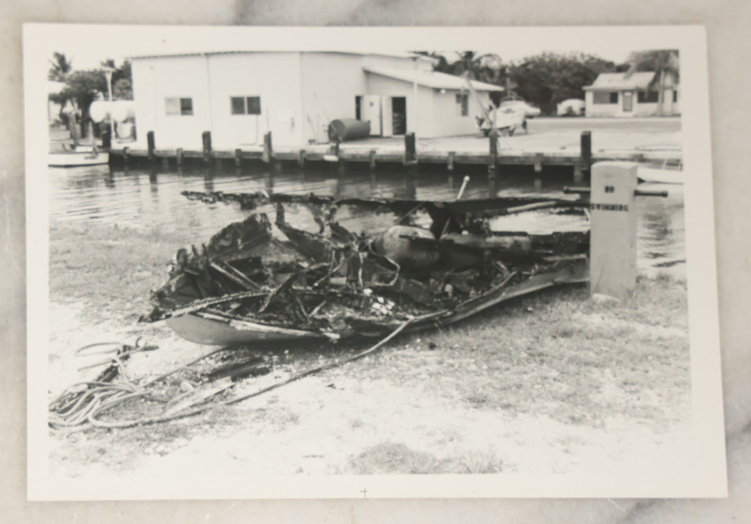 Lot 098 - Grouping Of Seven Vintage Snap Shot Photographs Including Child With Baby Deer Fawn, Man With Pelts, Teepee Campsite, Burned Boat, Etc.