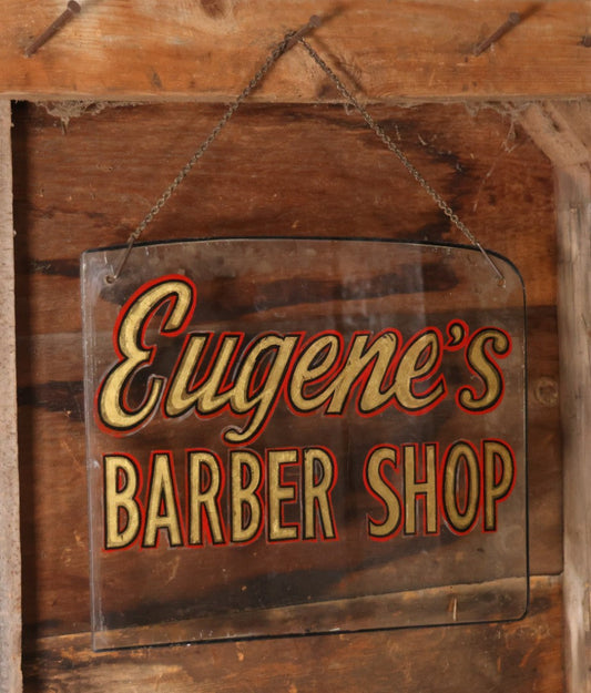 Vintage Reverse Painted Glass Sign For "Eugene's Barber Shop" With Chain Hanger, Painted On Ford Automotive Safety Glass, 16-7/8" x 14"