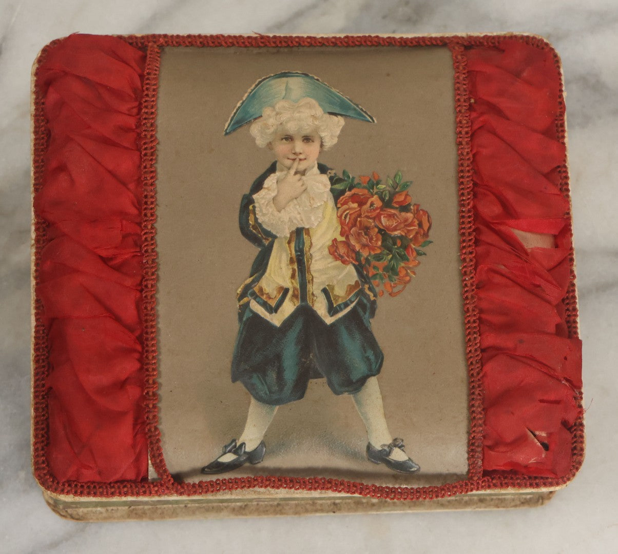 Lot 085 - Antique Paper Board Candy Box With Tufted Red Fabric, Blue Boy With Flowers Graphic On Cover