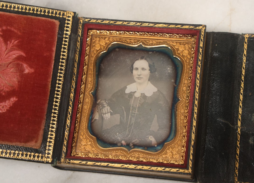 Lot 115 - Antique 1/6th Plate Daguerreotype Photograph Of Young Woman Wearing Black Lace Gloves And Large Brooch In Leatherette Folder Case With Latch, "Bijou" Lettering On Spine, Identified As Anna Matilda Blackledge, Note Partial Tear On Case Cover