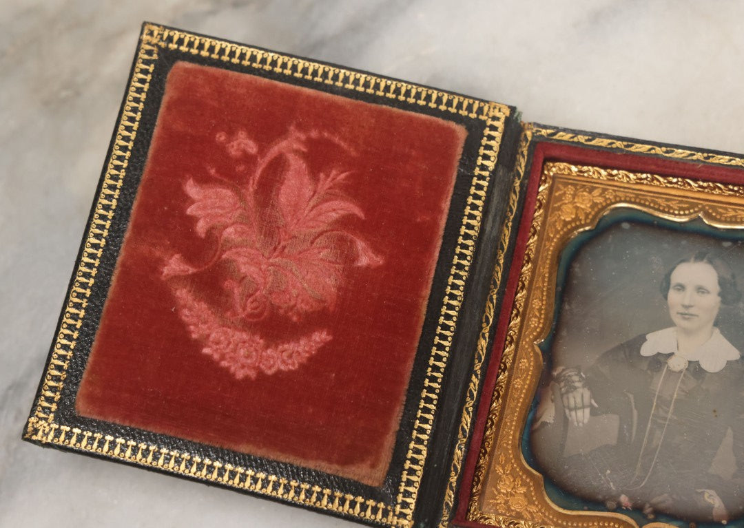 Lot 115 - Antique 1/6th Plate Daguerreotype Photograph Of Young Woman Wearing Black Lace Gloves And Large Brooch In Leatherette Folder Case With Latch, "Bijou" Lettering On Spine, Identified As Anna Matilda Blackledge, Note Partial Tear On Case Cover