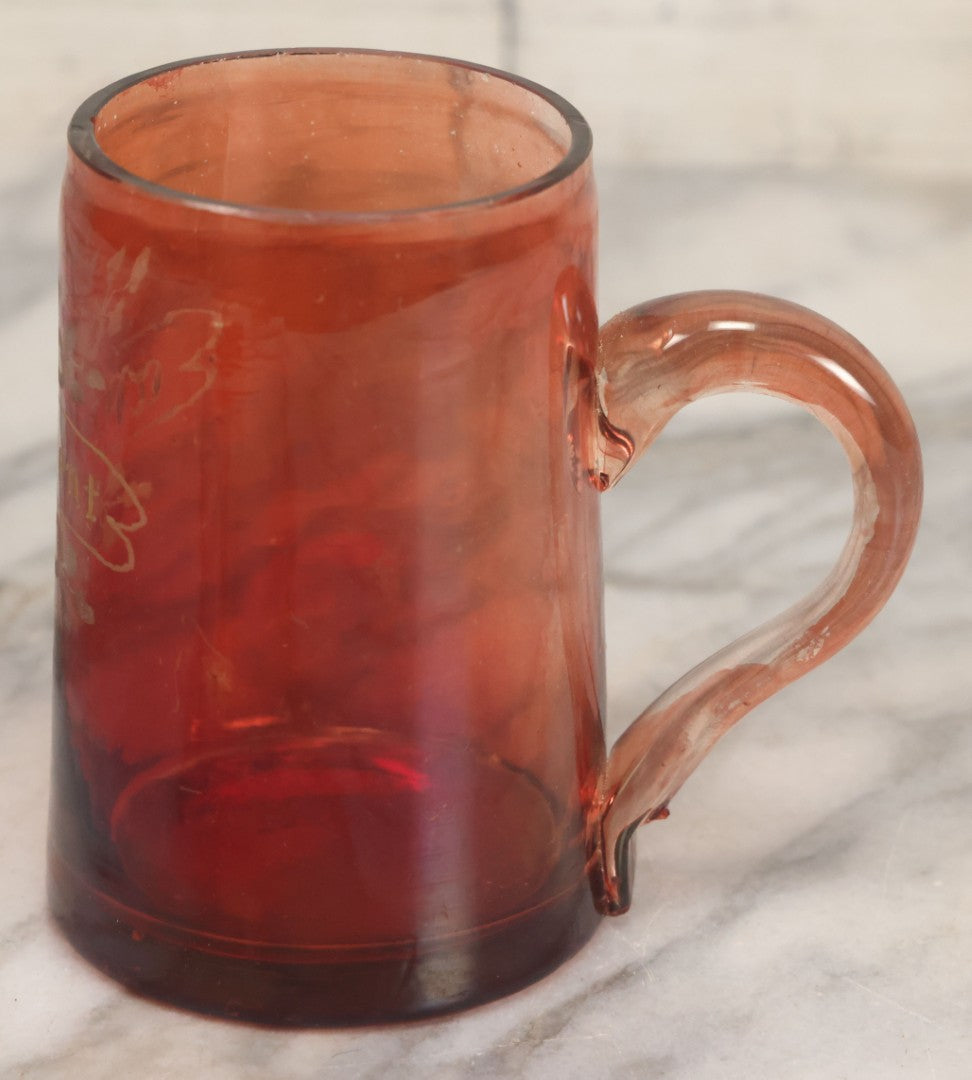 Lot 066 - Antique Ruby Glass Mug With Hand Etched, Hand Painted Details, "A Present" With Flowers, Note Chip To Bottom Of Handle, Rim