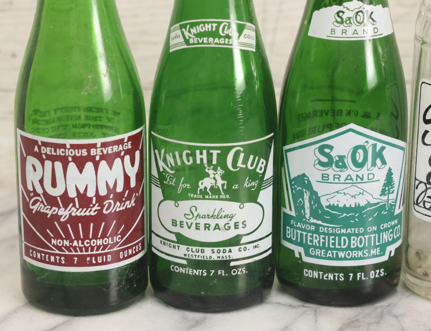 Lot 057 - Grouping Of Nine Vintage Glass Soda Bottles Including Coca-Cola, Cott, Min-R-Ize, Elk Club, Knight Club, Nugget, S&O'K, Rummy Grapefruit Drink, And Stafford Springs