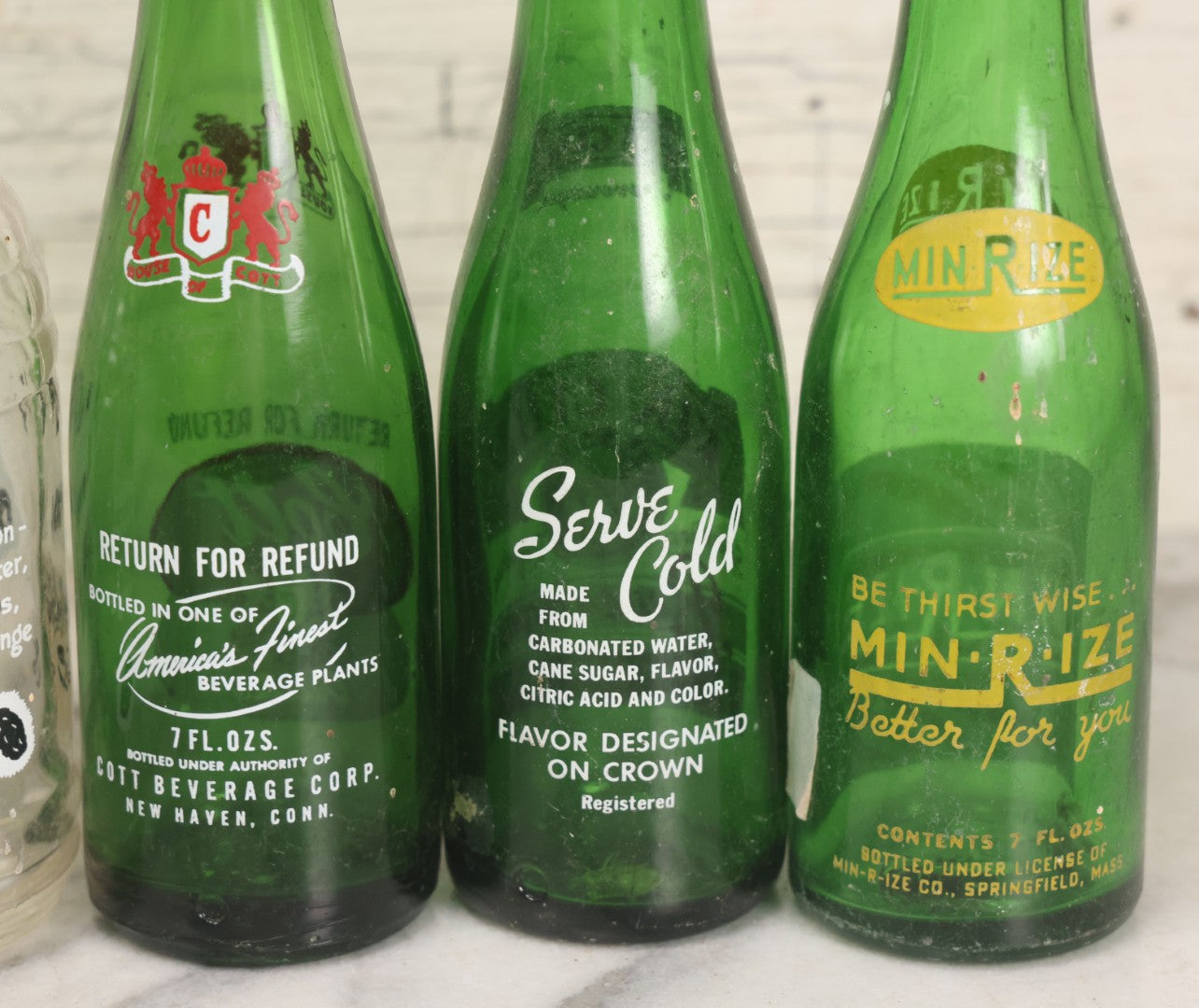 Lot 057 - Grouping Of Nine Vintage Glass Soda Bottles Including Coca-Cola, Cott, Min-R-Ize, Elk Club, Knight Club, Nugget, S&O'K, Rummy Grapefruit Drink, And Stafford Springs