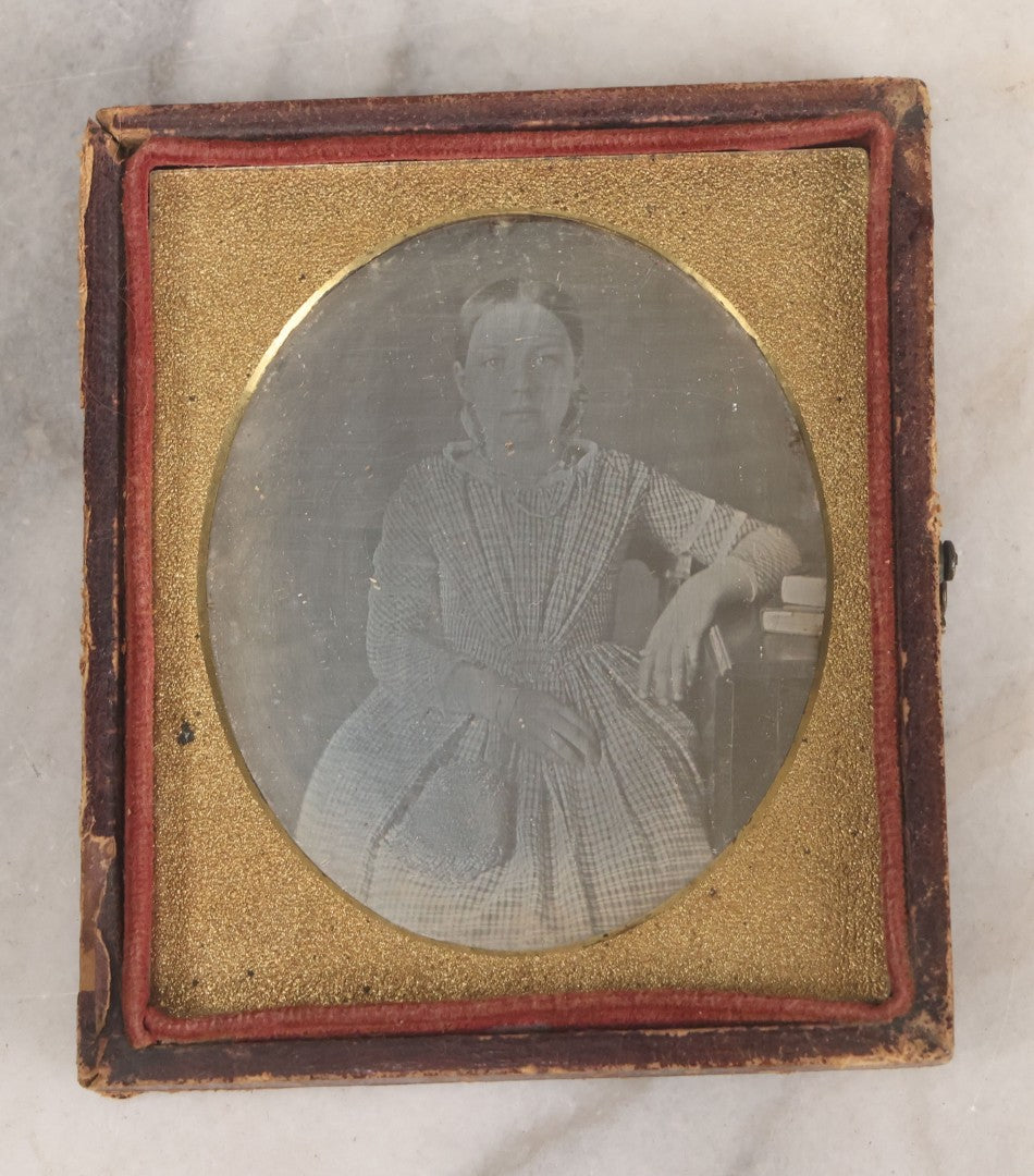 Lot 069 - Antique 1/6th Plate Daguerreotype Photograph Of Young Girl In Plaid Dress With Beaded Handbag Seated Beside A Table With Books In Half Leatherette Case