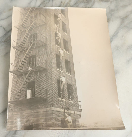 Lot 113 - Vintage Large Format Glossy Photograph Of Men Climbing Ladder On Brick Tower, Likely Firefighter Training Related