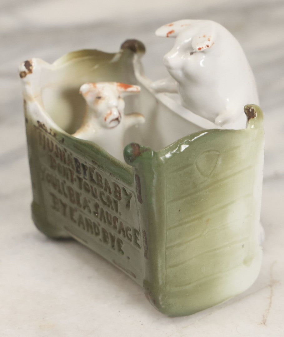Lot 027 - Antique Porcelain Novelty Vessel With Mama Pig And Pig In Cradle, "Hush Hushabye Baby, Don't You Cry, You'll Be A Sausage Bye And Bye," Stamped Germany, With Remnants Of Original Paint, Note Cracks And Repairs