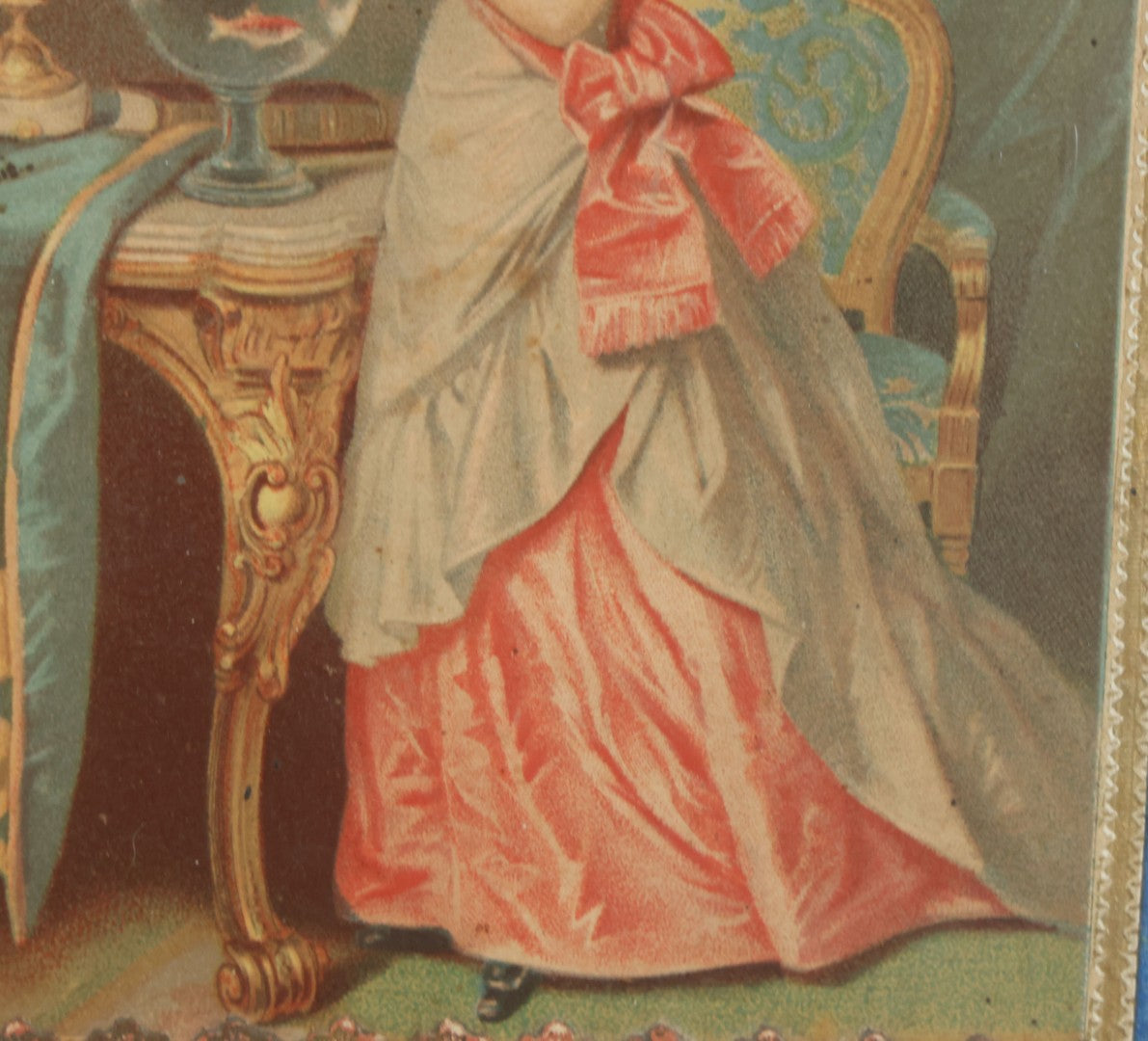 Lot 032 - Antique Lithographed Paper Board Box Cover Depicting Young Woman In Pink Dress Playing With Her Goldfish In Period Etched Wooden Frame, 10-5/8" x 11-3/4"