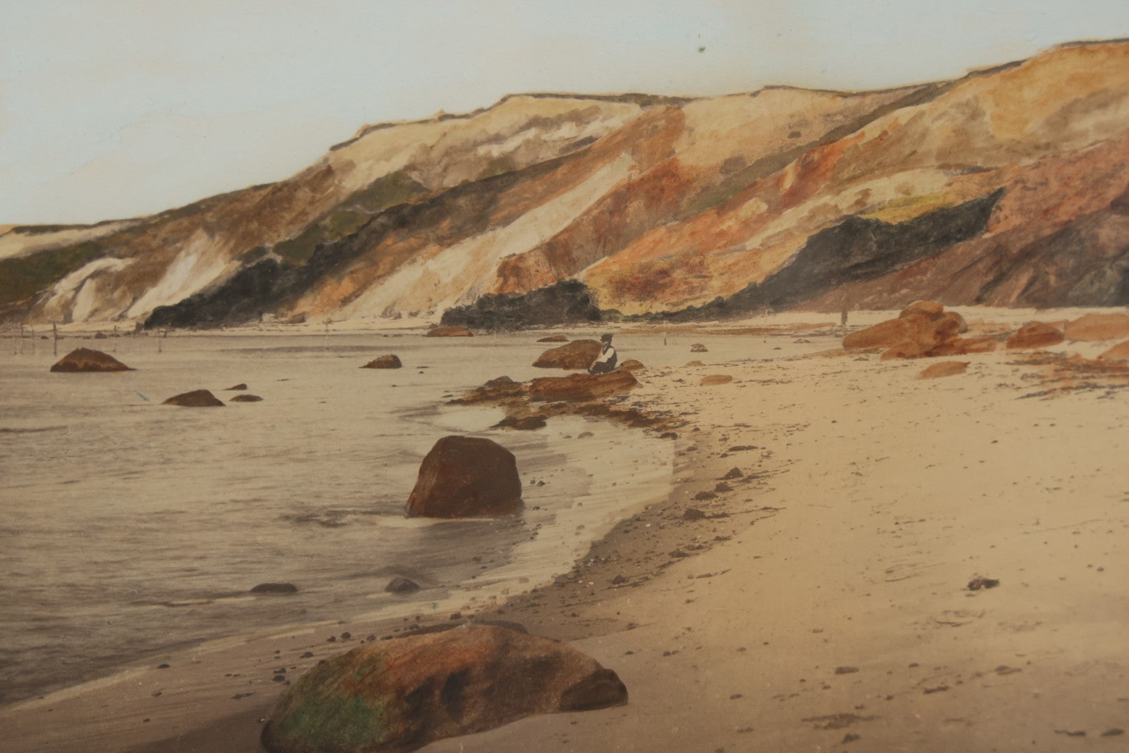 Lot 033 - Antique Painted Over Photograph Of Oceanside Cliffs And Beach With Child Seated On Rocks Likely Gay Head Cliffs, Martha's Vineyard, Massachusetts, In Original Frame, 17-1/2" x 15-1/2"