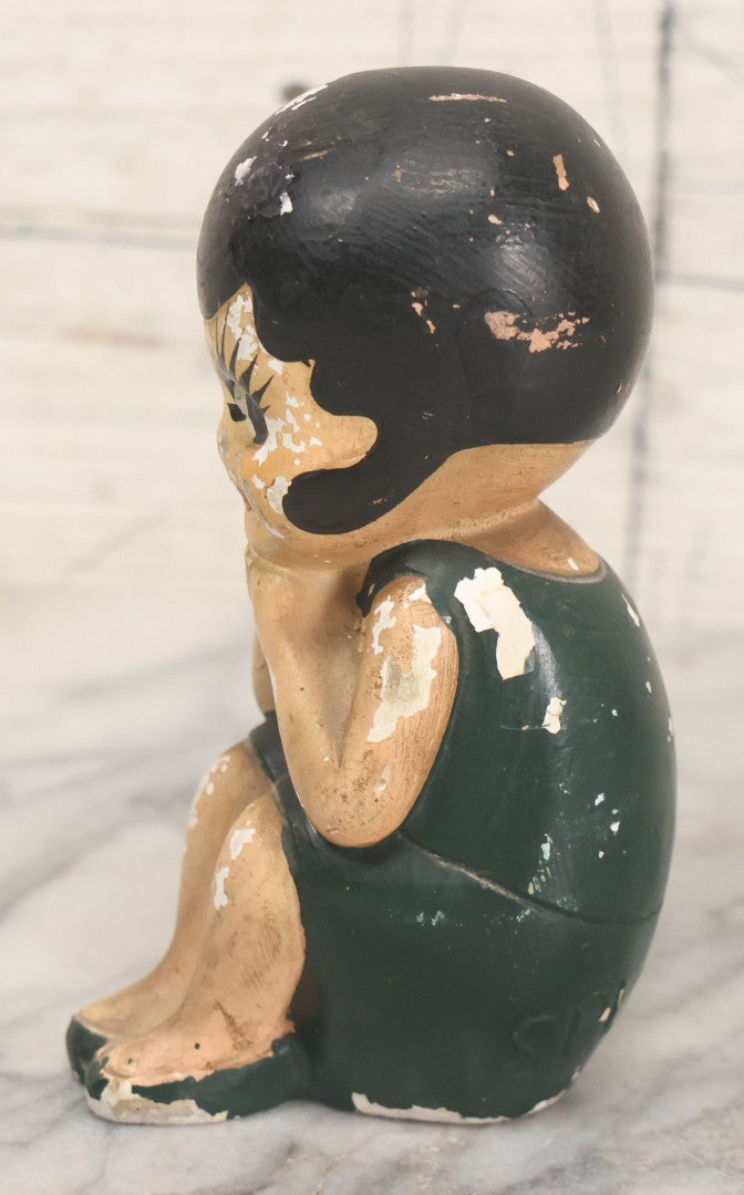 Lot 044 - Vintage Chalkware Kewpie-Style Crouching Flapper Doll With Black Hair And Green Dress, Back Marked "Splash Me", Note Paint Chipping And Wear, 4-3/4" Height