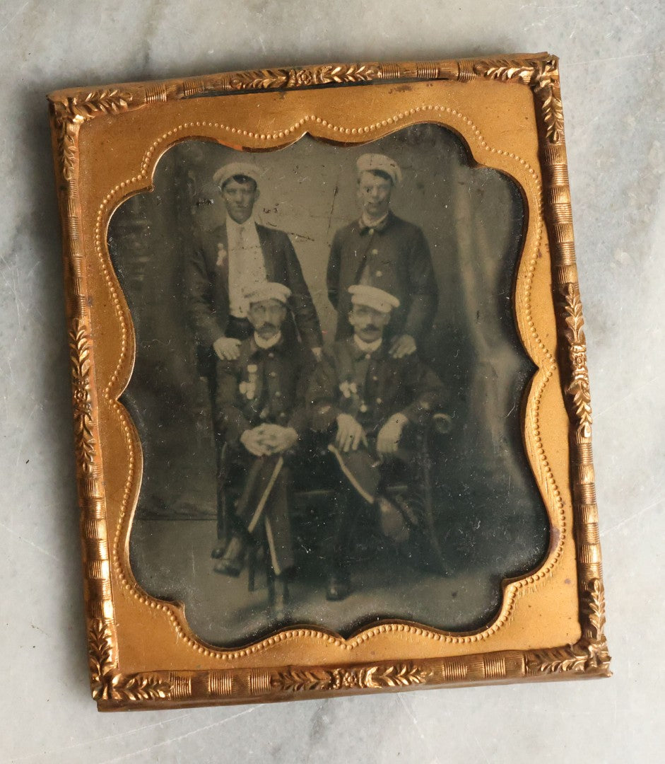 Lot 070 - Antique 1/6th Plate Tintype Photograph With Brass Mat And Preserver Of Four Well Dressed Fraternal Men Wearing Hats And Badges