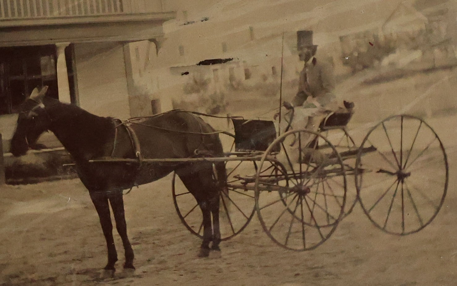 Lot 074 - Antique Outdoor Tintype Photograph Of Man In Stovepipe Hat Sitting On Horse Drawn Cart In Front Of A Building With Partial Sign Visible And Houses In Background