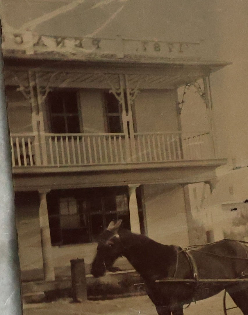 Lot 074 - Antique Outdoor Tintype Photograph Of Man In Stovepipe Hat Sitting On Horse Drawn Cart In Front Of A Building With Partial Sign Visible And Houses In Background