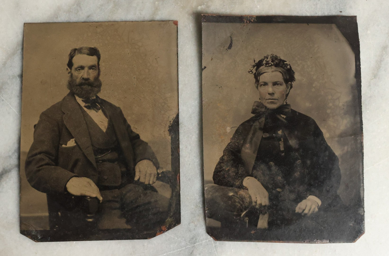 Lot 075 - Pair Of Tintype Photographs Of An Old Man With Large Hands And Unusual Face And Big Bushy Beard, And Stern Woman With Large Neck Bow