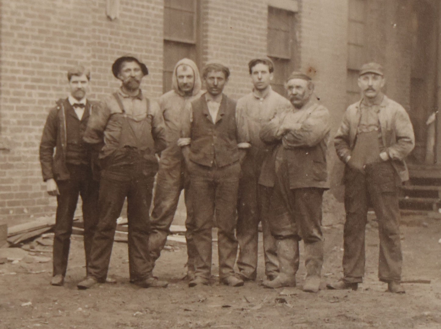 Lot 071 - Antique Boarded Occupational Photograph Of Group Of Seven Dirty Workers Posing In Work Clothes Outside Brick Workplace