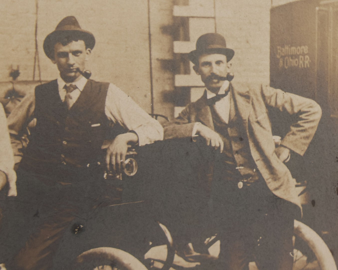 Lot 072 - Antique Boarded Occupational Photograph Of Three Men Smoking Pipes And Posing With Turn Of The Century Automobile, With Baltimore & Ohio Railroad Carriage Visible In Background, Handwritten Note On Verso, Dated October 9, 1901