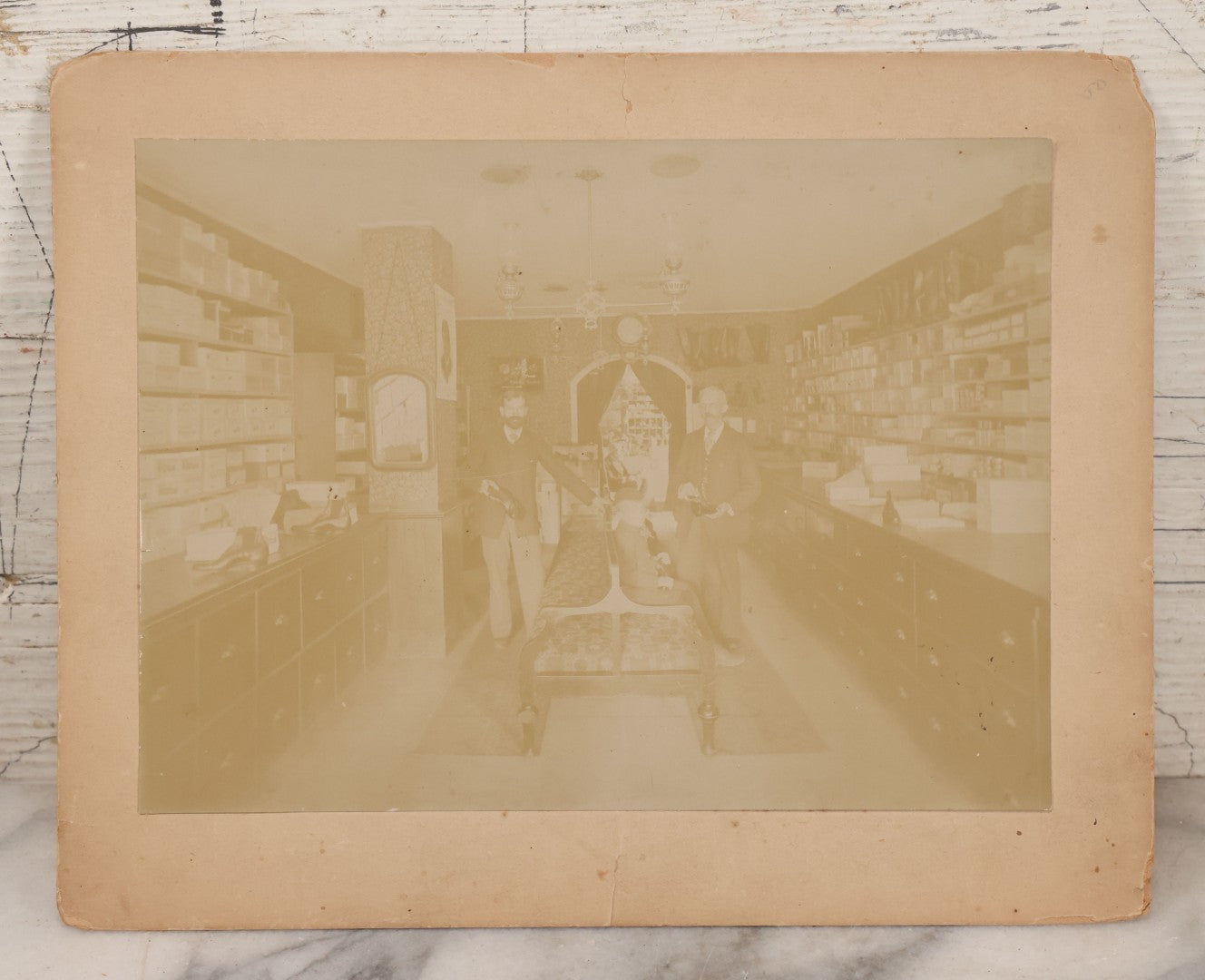Lot 076 - Antique Boarded Photograph Of Three Men And Young Boy In Boot And Shoe Store, With Products And Advertising Visible In Photo